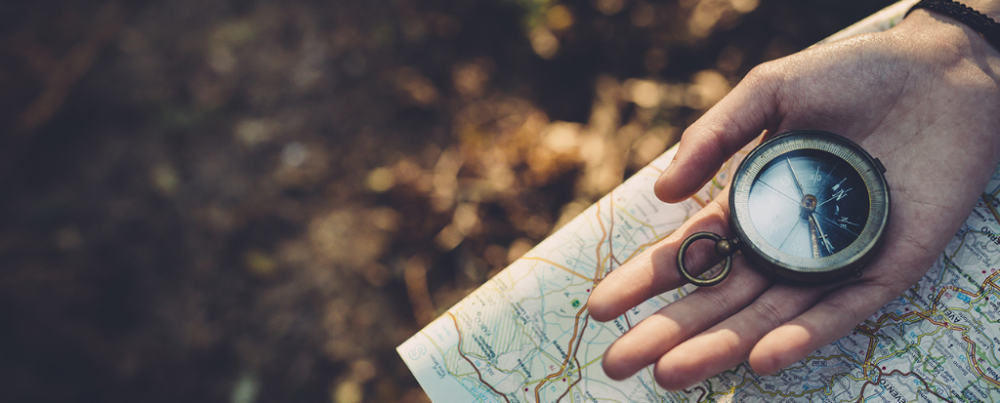 Main tenant une boussole sur une carte illustrant la stratégie de relation client 2026