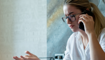 portrait-young-office-worker-woman-sitting-office-desk-with-documents-talking-mobile-phone-nervous-stressed-working-office.